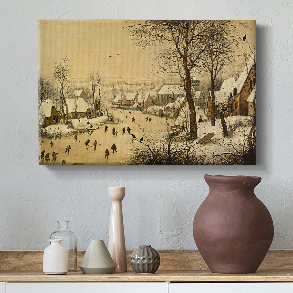Canvas art print featuring a rustic village scene with skaters and snow-covered terrain, styled above a decorative console