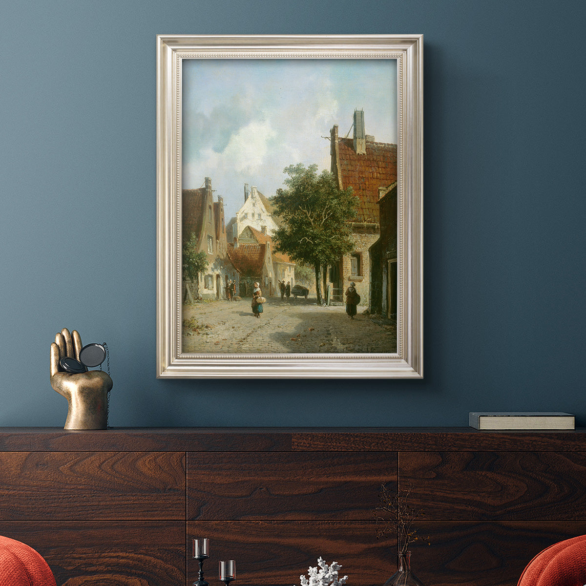 Rustic European street scene painting by Adriaan Eversen in an ornate champagne frame displayed in a dark-toned interior setting.