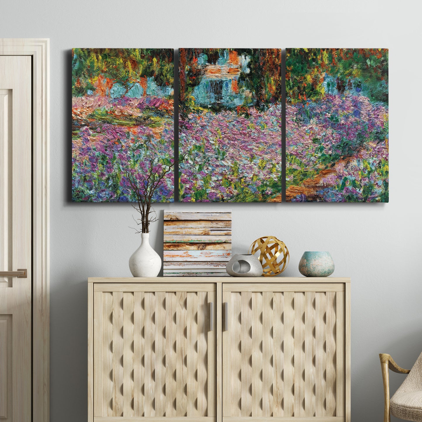 Three-panel canvas wall art featuring blooming irises in garden bed, displayed above a cabinet in an entryway.