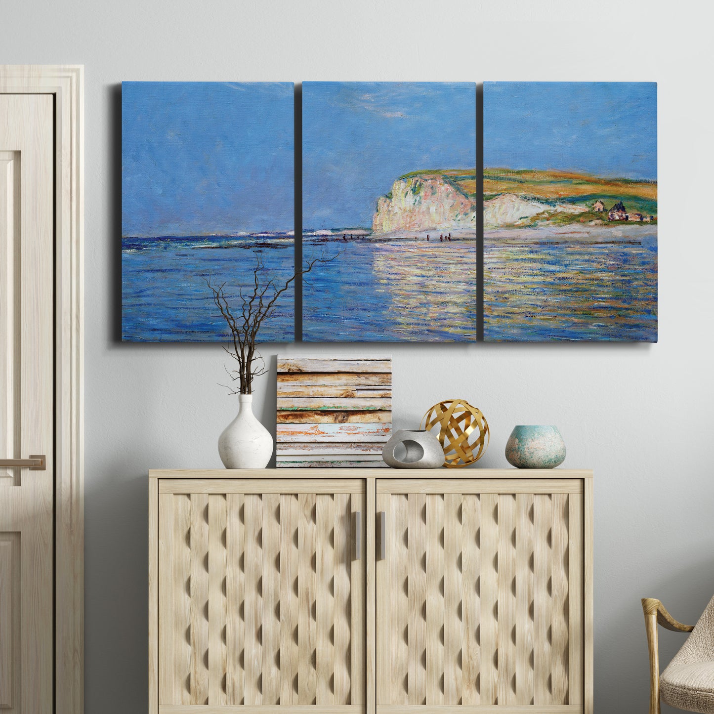 Three-panel canvas wall art featuring white cliffs rising above sea, displayed above a cabinet in an entryway.