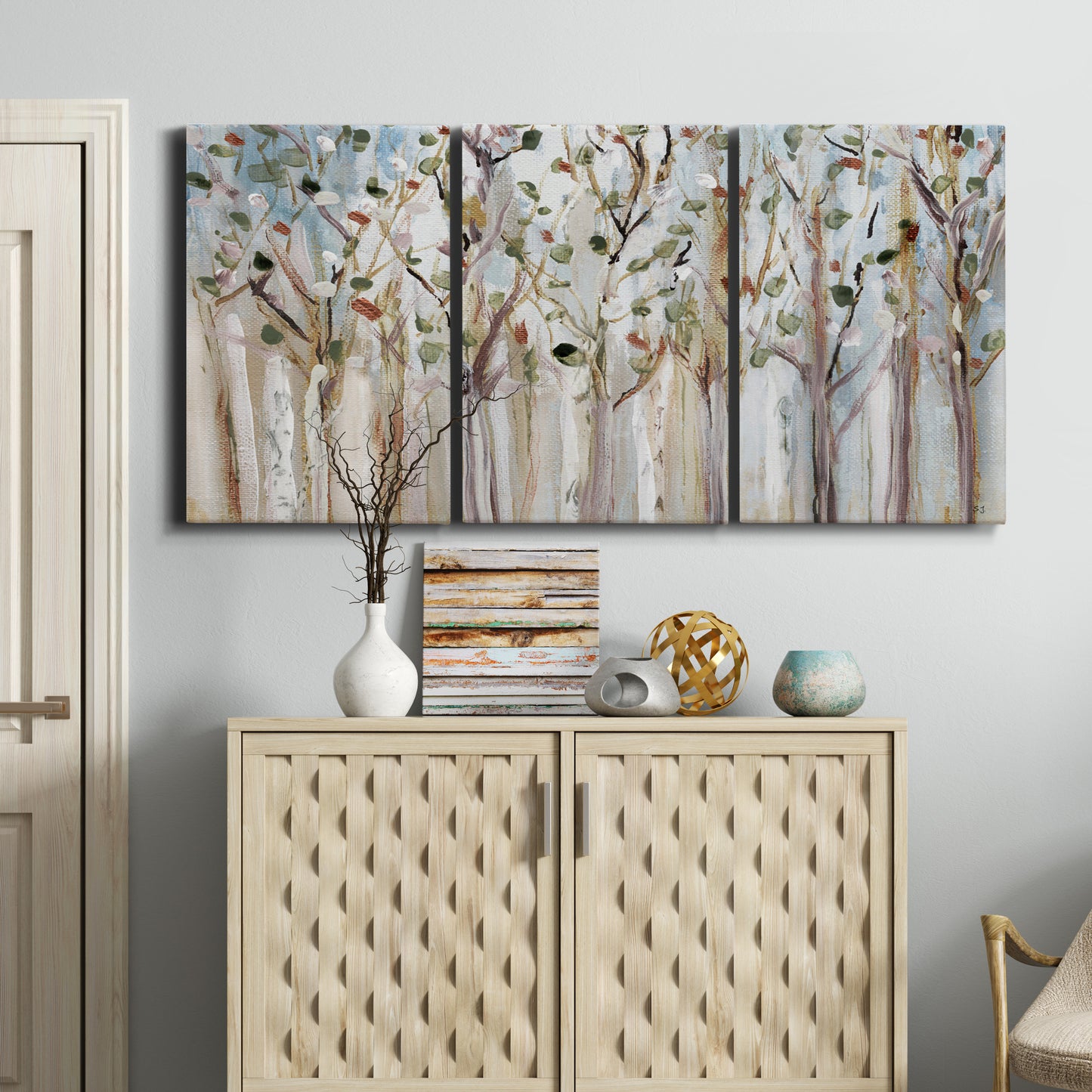 Three-panel canvas wall art featuring bare birch trees in winter forest, displayed above a cabinet in an entryway.