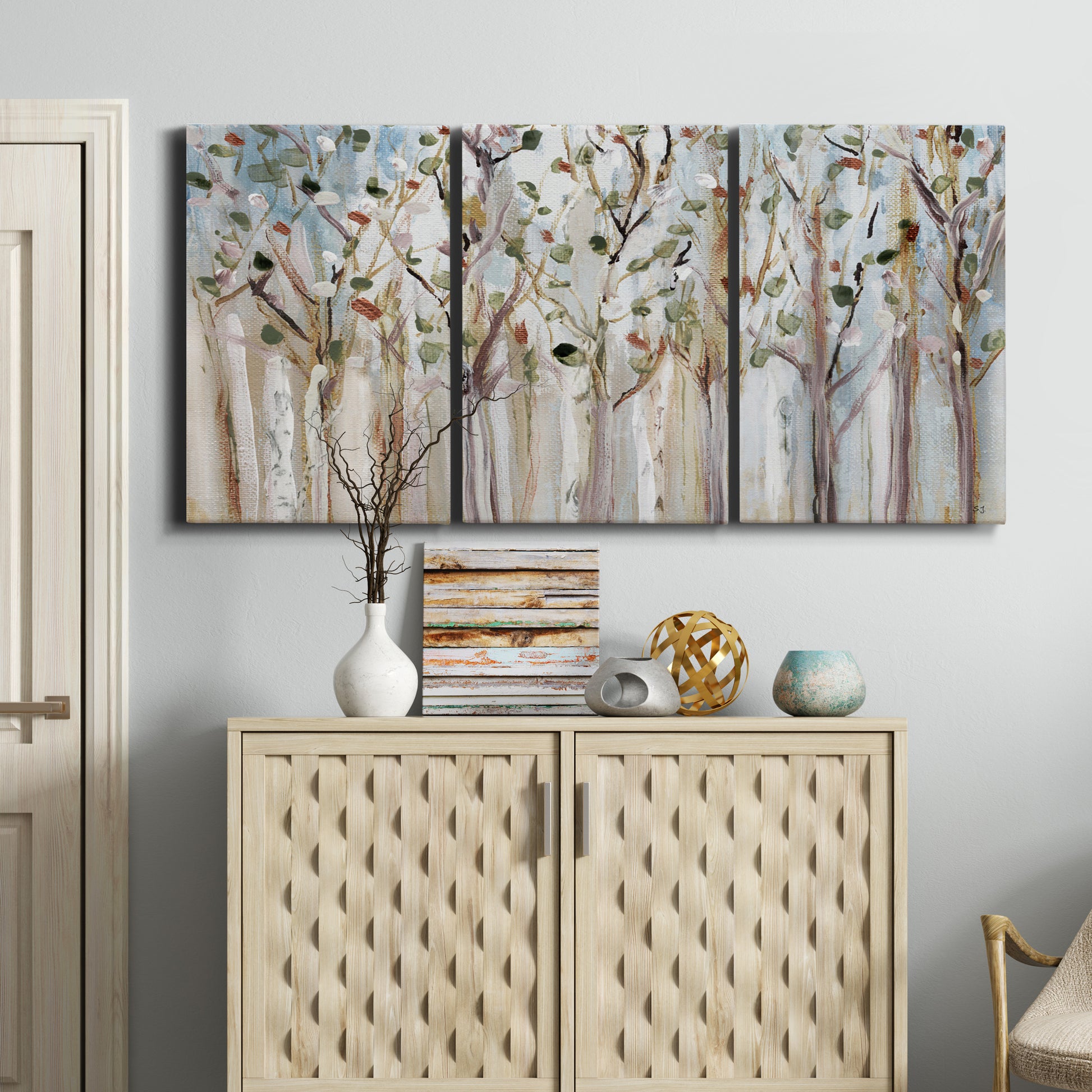 Three-panel canvas wall art featuring bare birch trees in winter forest, displayed above a cabinet in an entryway.