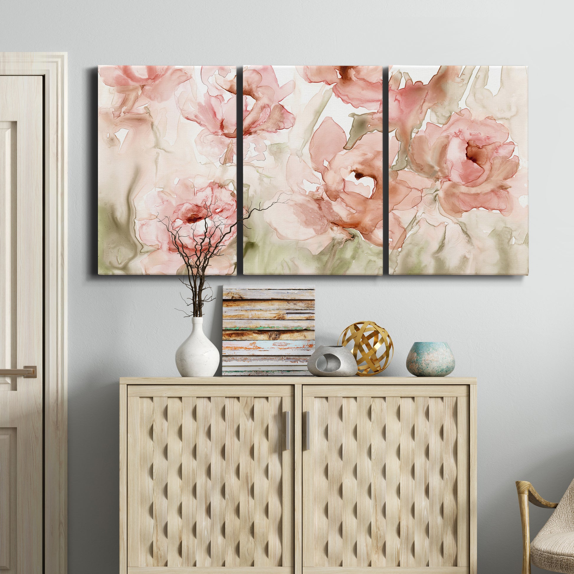 Three-panel canvas wall art featuring spring floral blossoms in bloom, displayed above a cabinet in an entryway.