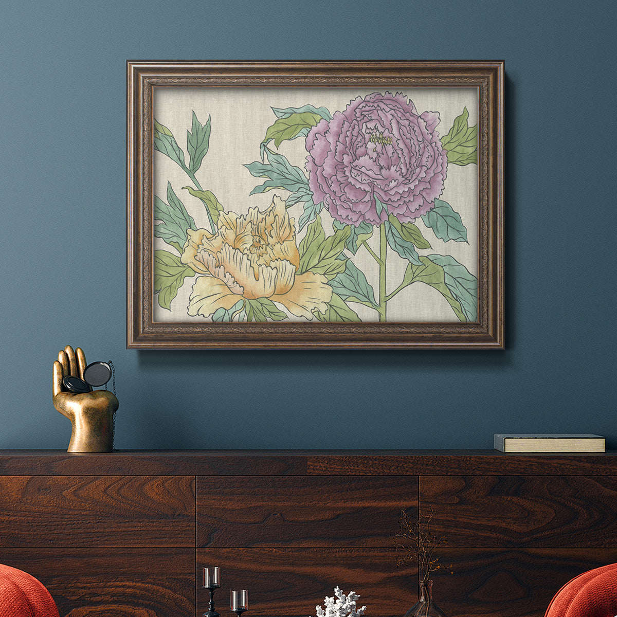 Contemporary peony flower illustration in an ornate traditional bronze frame displayed in a dark-toned interior setting.