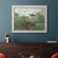 Impressionist garden landscape at Argenteuil by Claude Monet in an ornate weathered white frame displayed in a dark-toned interior setting.