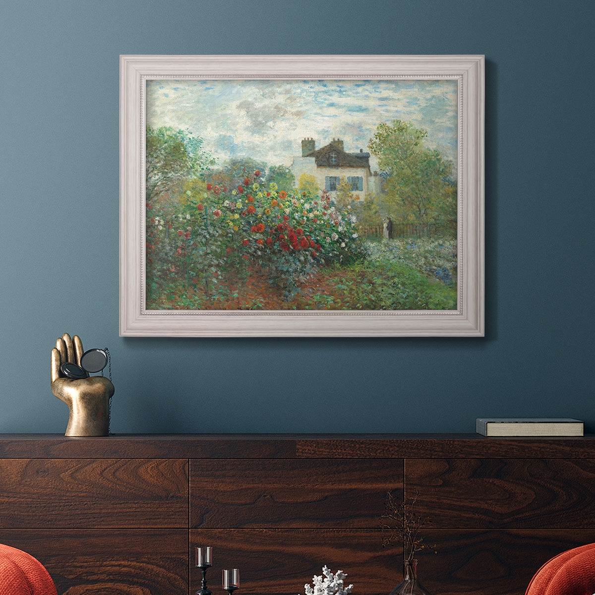Impressionist garden landscape at Argenteuil by Claude Monet in an ornate weathered white frame displayed in a dark-toned interior setting.