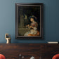 Classical interior scene of a woman weaving flowers by Godfried Schalcken in an ornate black frame with gilded inner detail displayed in a dark-toned interior setting.