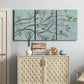 Three-panel canvas wall art featuring blue sky with flowering branches, displayed above a cabinet in an entryway.