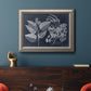 Decorative botanical foliage drawing on navy background in an ornate vintage silver frame displayed in a dark-toned interior setting.
