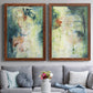 Set of two maple barnwood framed canvas prints depicting paired nature-inspired mixed-media abstracts with vertical organic marks, pale light passages, and weathered surfaces above a sofa in a contemporary living room.