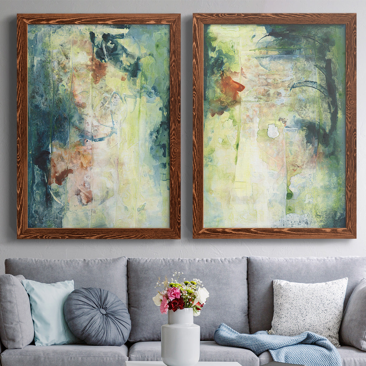 Set of two maple barnwood framed canvas prints depicting paired nature-inspired mixed-media abstracts with vertical organic marks, pale light passages, and weathered surfaces above a sofa in a contemporary living room.