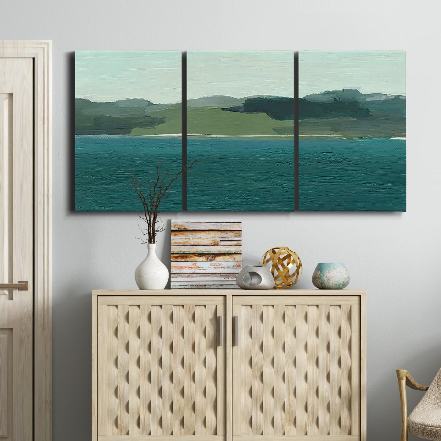 Three-panel canvas wall art featuring calm lake water under open sky, displayed above a cabinet in an entryway.