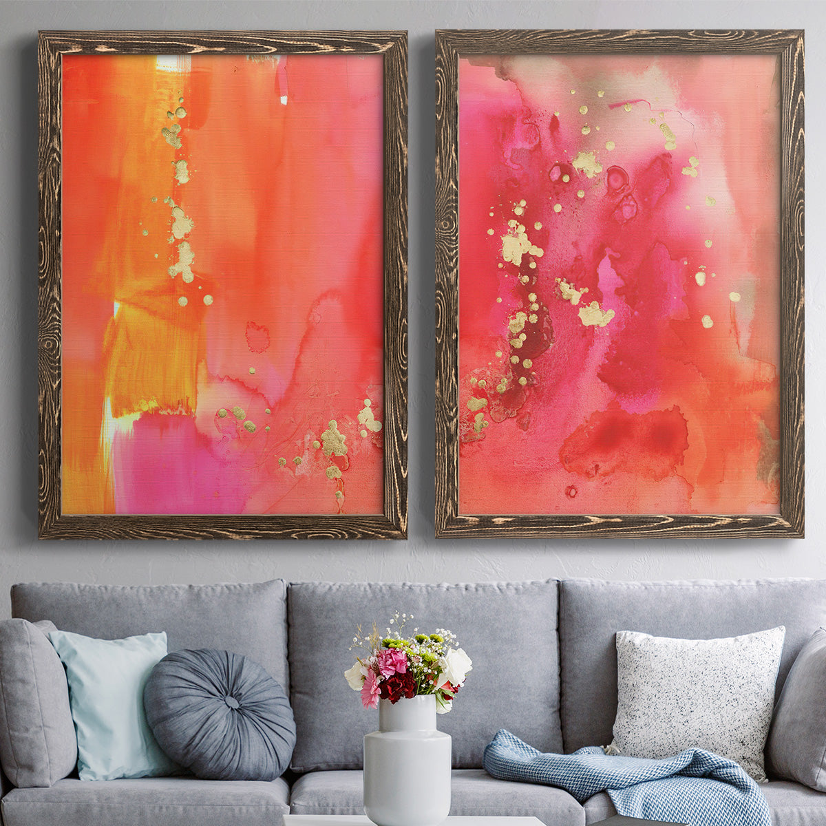 Set of two walnut barnwood framed canvas prints depicting paired glamorous fluid abstracts with translucent warm washes, drips, and scattered metallic accents above a sofa in a contemporary living room.