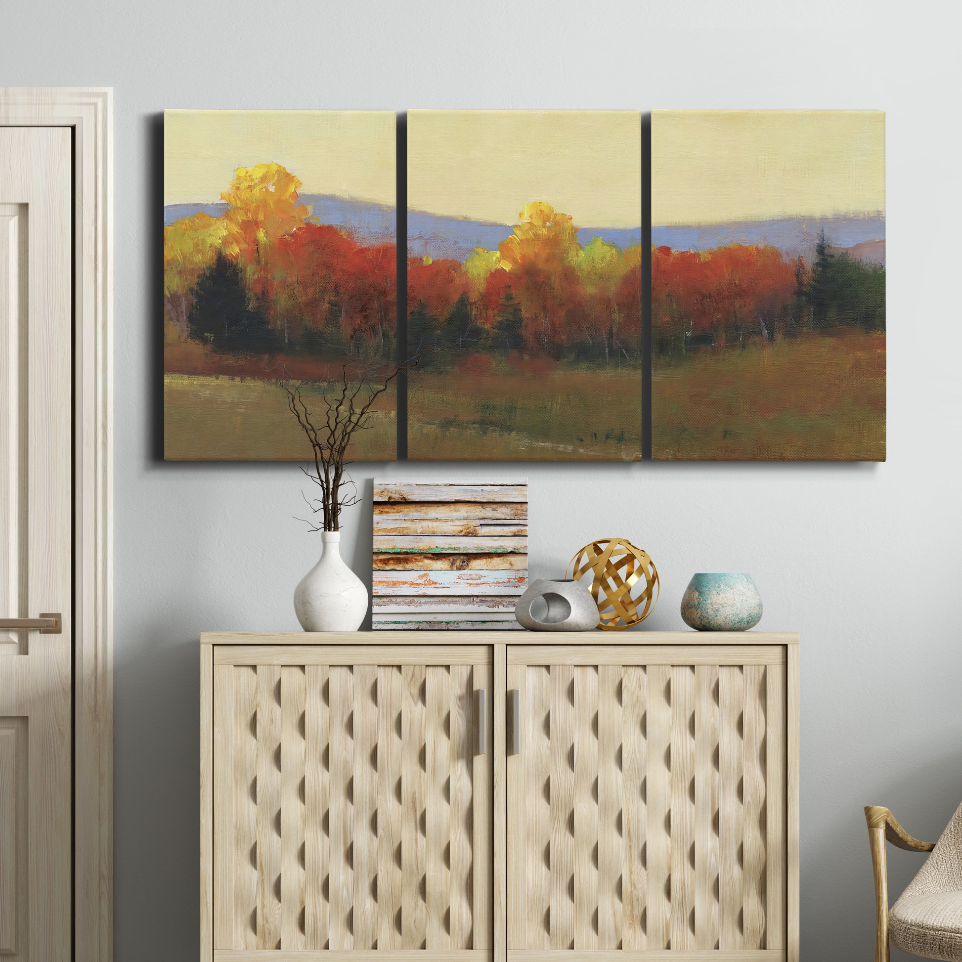 Three-panel canvas wall art featuring autumn landscape changing foliage, displayed above a cabinet in an entryway.