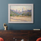 Impressionist valley landscape in southern France by Claude Monet in an ornate weathered white frame displayed in a dark-toned interior setting.