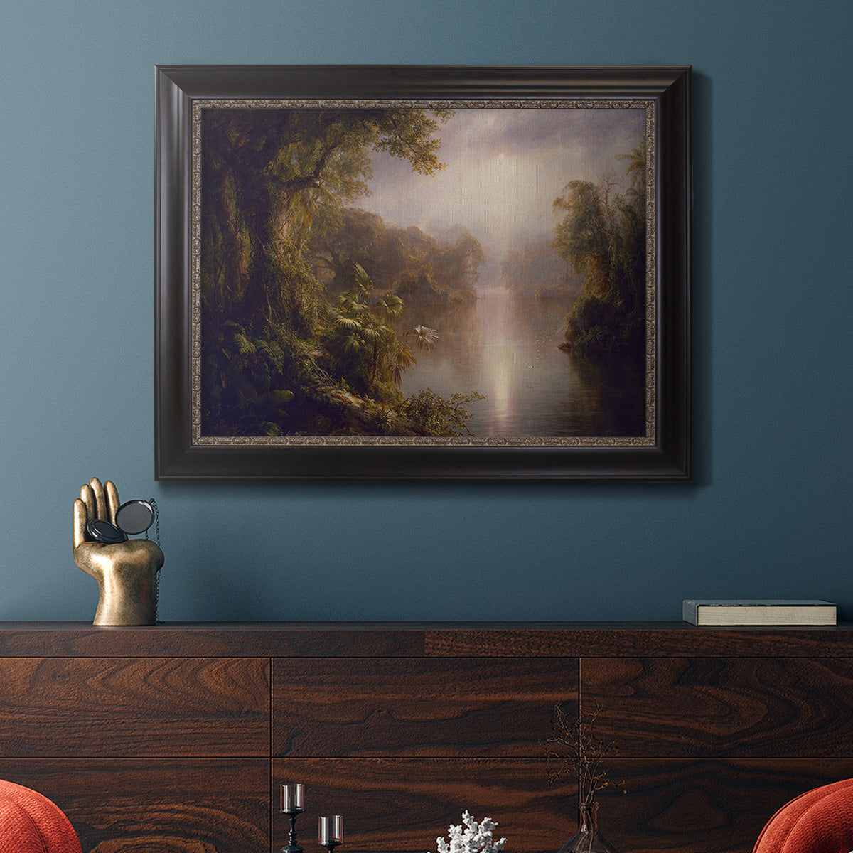 Luminous romantic landscape painting by Frederic Edwin Church in an ornate black frame with gilded inner detail displayed in a dark-toned interior setting.