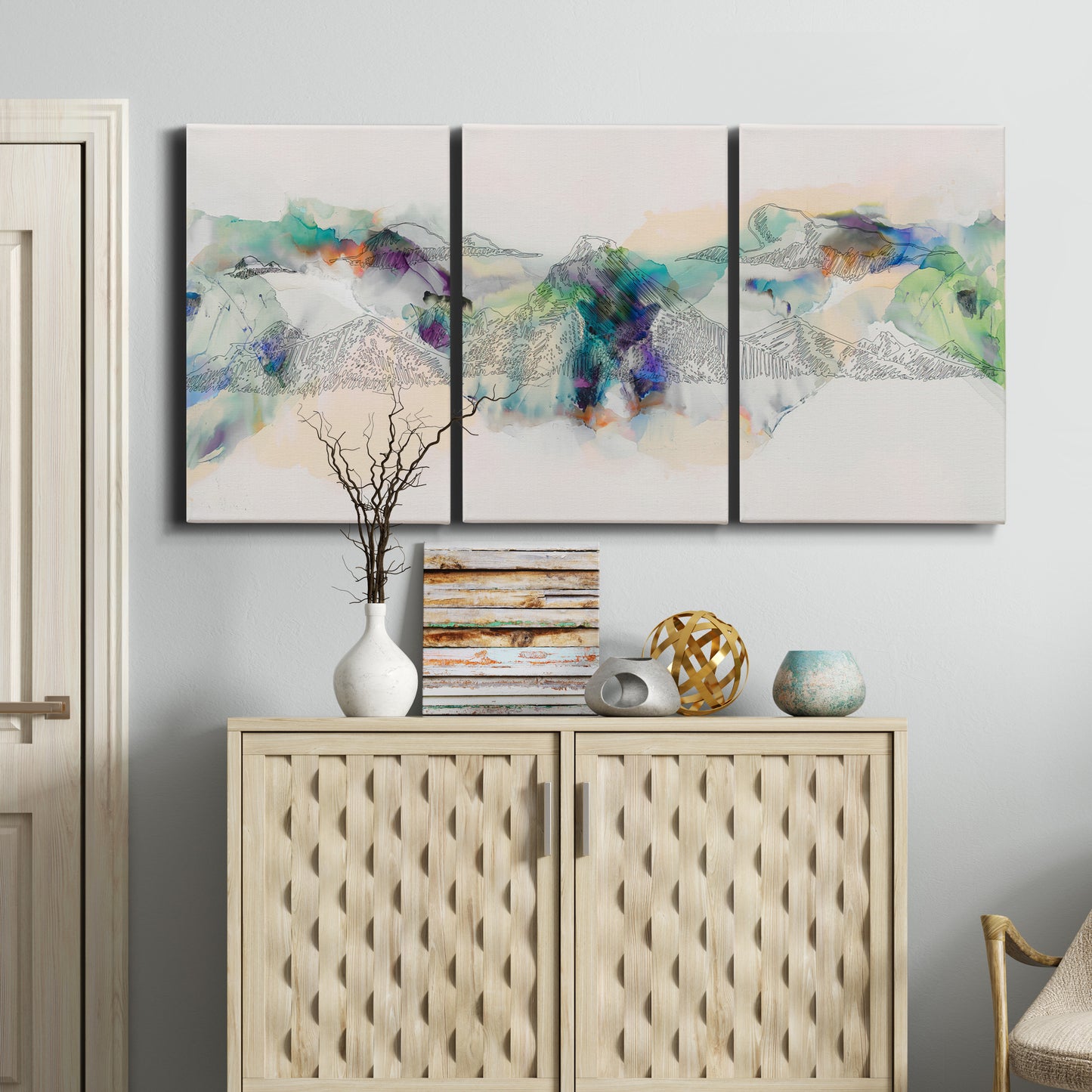 Three-panel canvas wall art featuring abstract mountain range watercolor, displayed above a cabinet in an entryway.