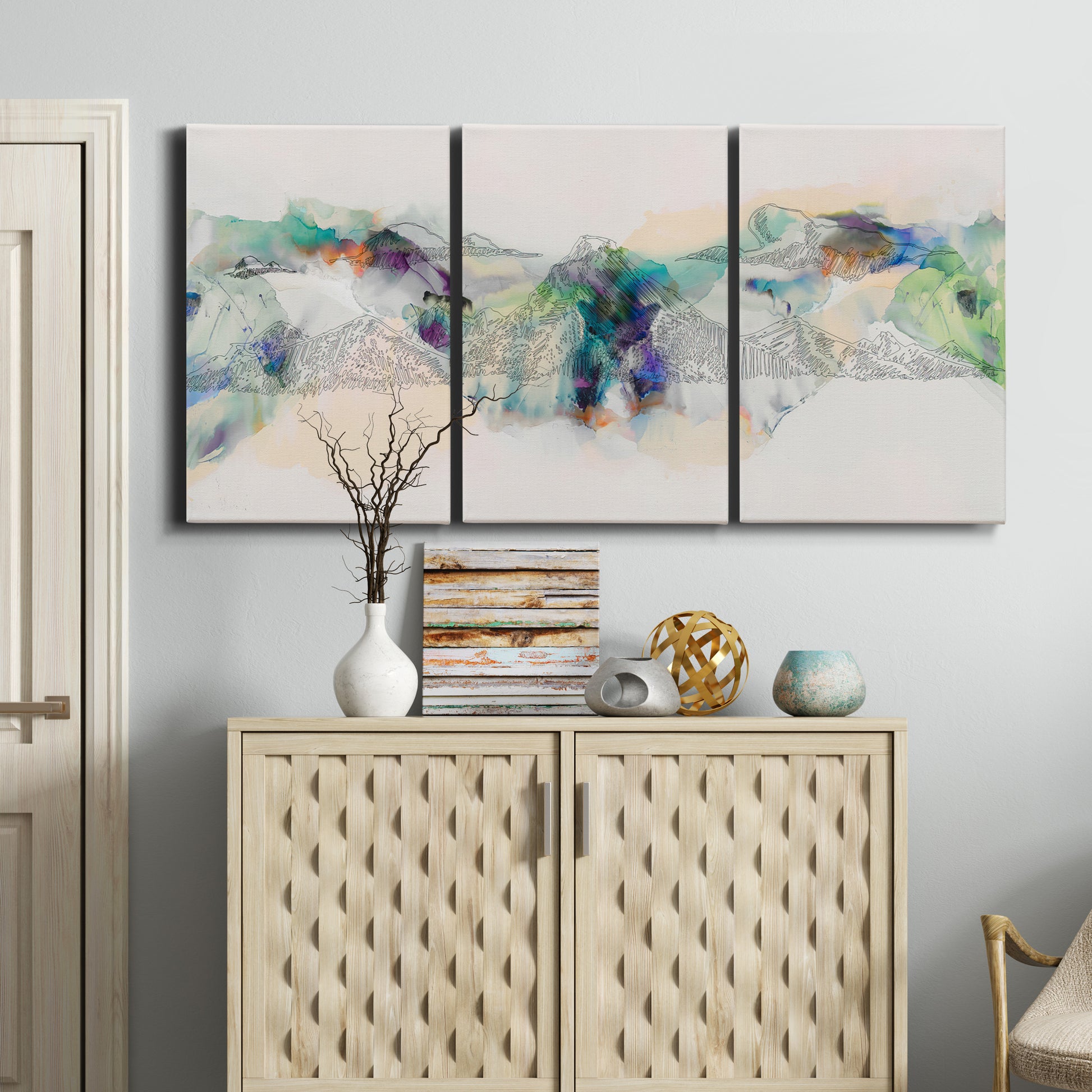 Three-panel canvas wall art featuring abstract mountain range watercolor, displayed above a cabinet in an entryway.