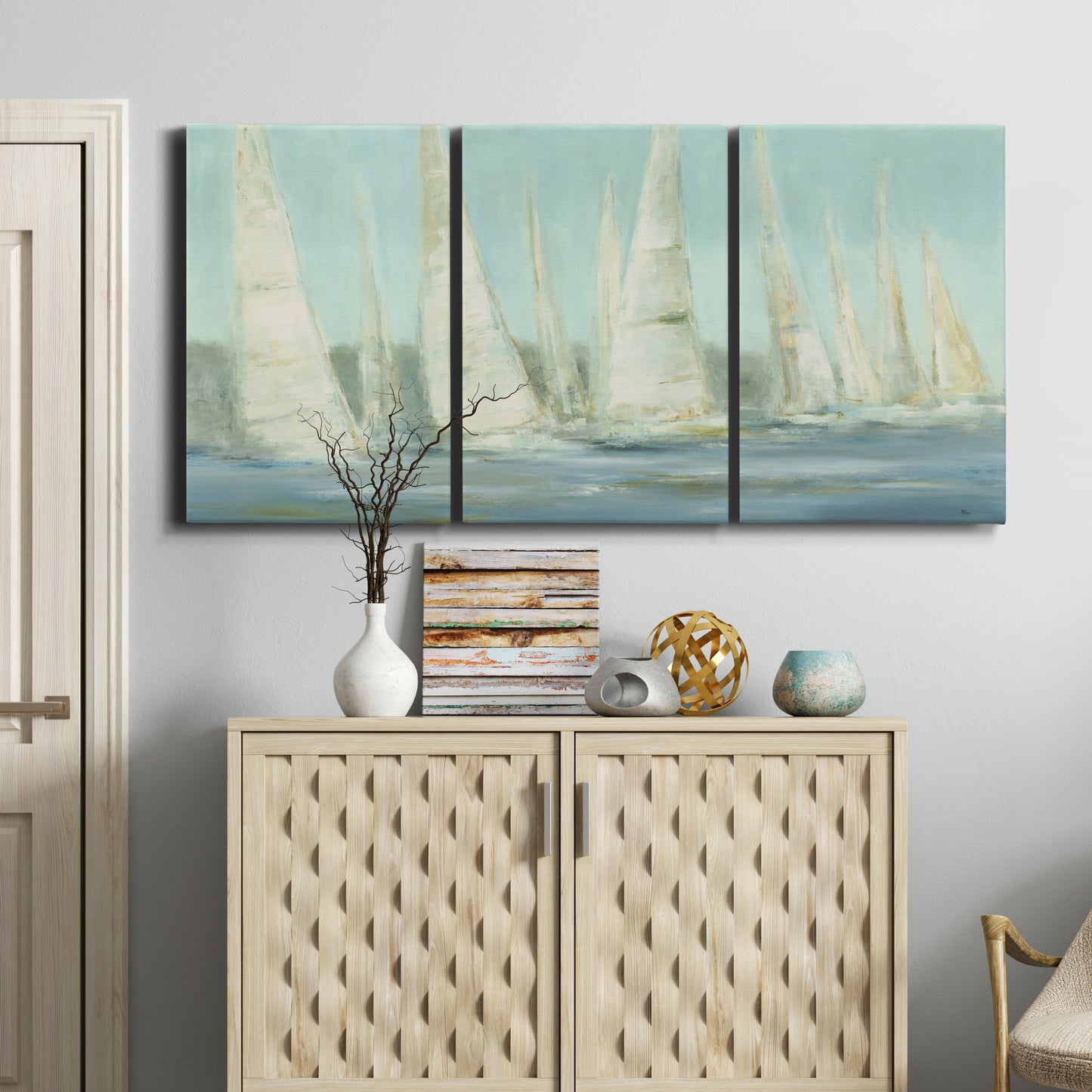 Three-panel canvas wall art featuring sailboats silhouetted at sunrise, displayed above a cabinet in an entryway.