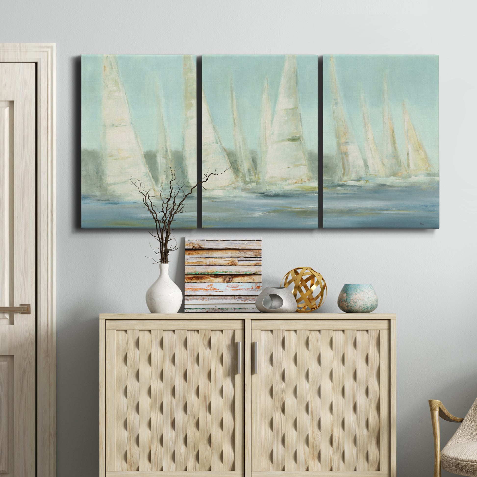 Three-panel canvas wall art featuring sailboats silhouetted at sunrise, displayed above a cabinet in an entryway.