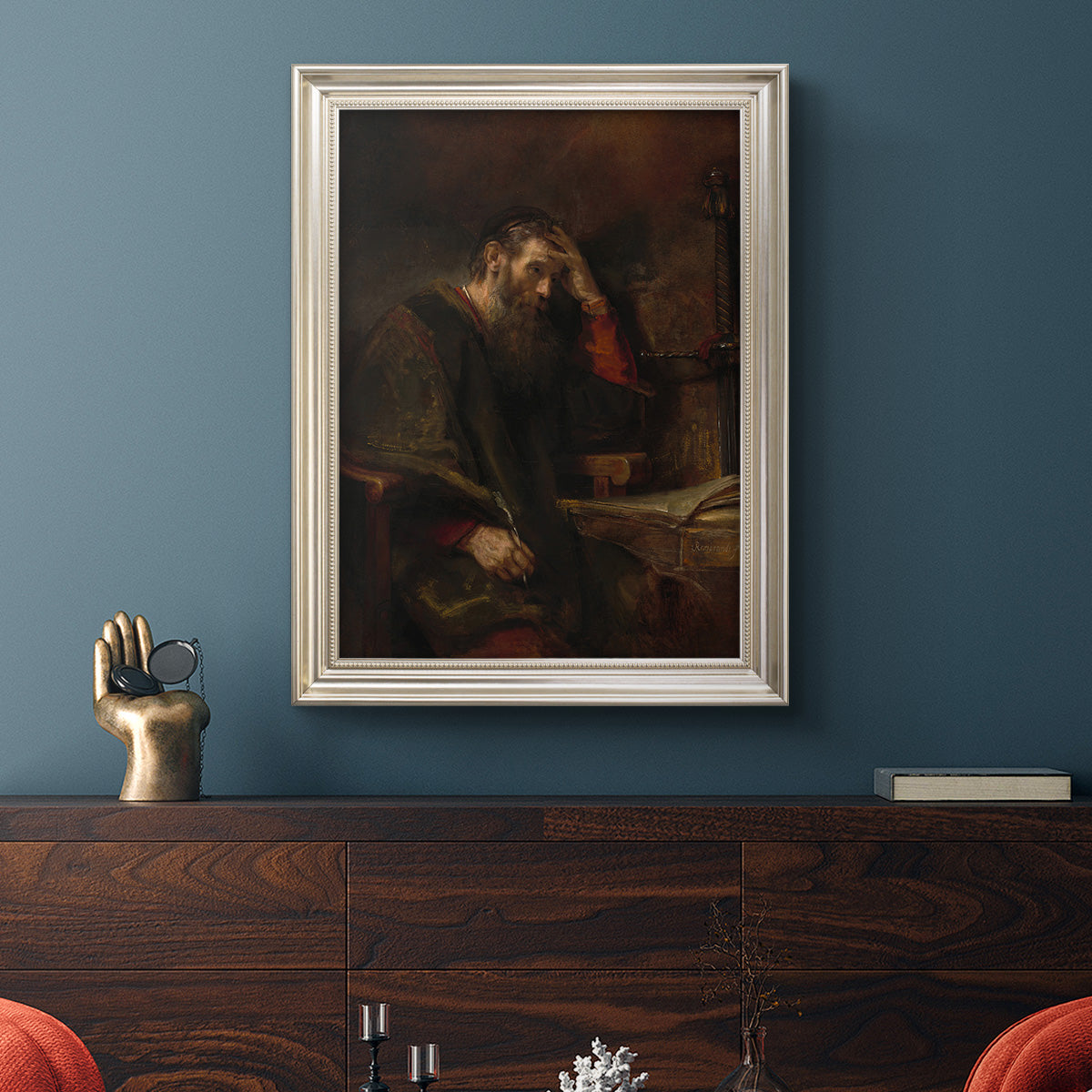 Classical religious portrait of Paul the Apostle by Rembrandt van Rijn in an ornate champagne frame displayed in a dark-toned interior setting.