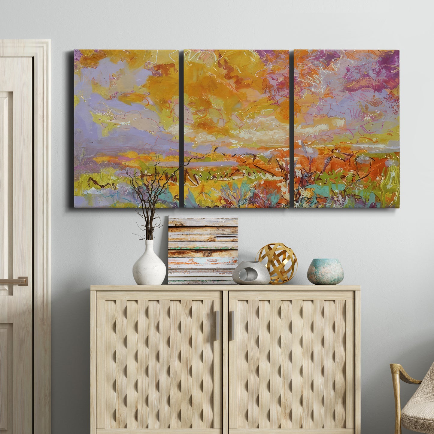 Three-panel canvas wall art featuring abstract meadow inspired color fields, displayed above a cabinet in an entryway.