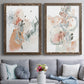 Set of two walnut barnwood framed canvas prints depicting paired abstract watercolor botanicals with scribbled petals, translucent washes, and drifting stems above a sofa in a contemporary living room.