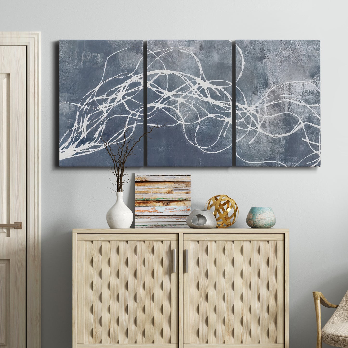 Three-panel canvas wall art featuring coastal shoreline at golden hour, displayed above a cabinet in an entryway.