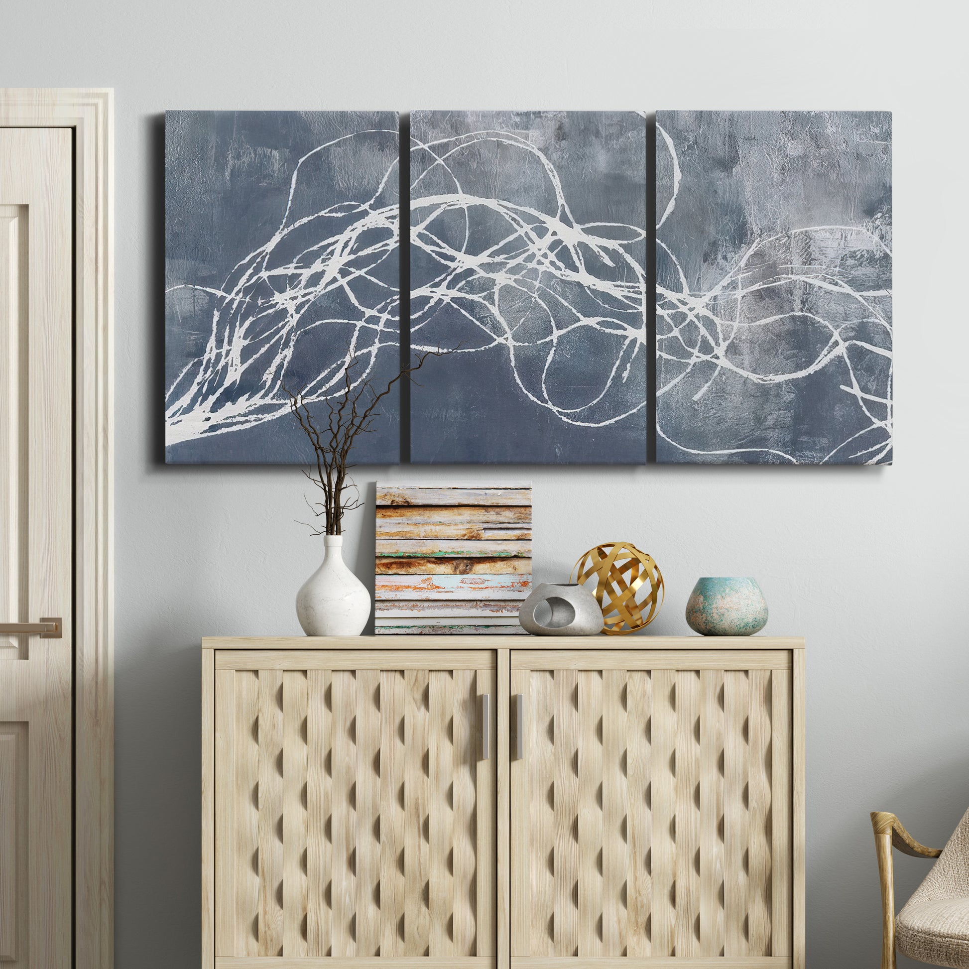 Three-panel canvas wall art featuring coastal shoreline at golden hour, displayed above a cabinet in an entryway.