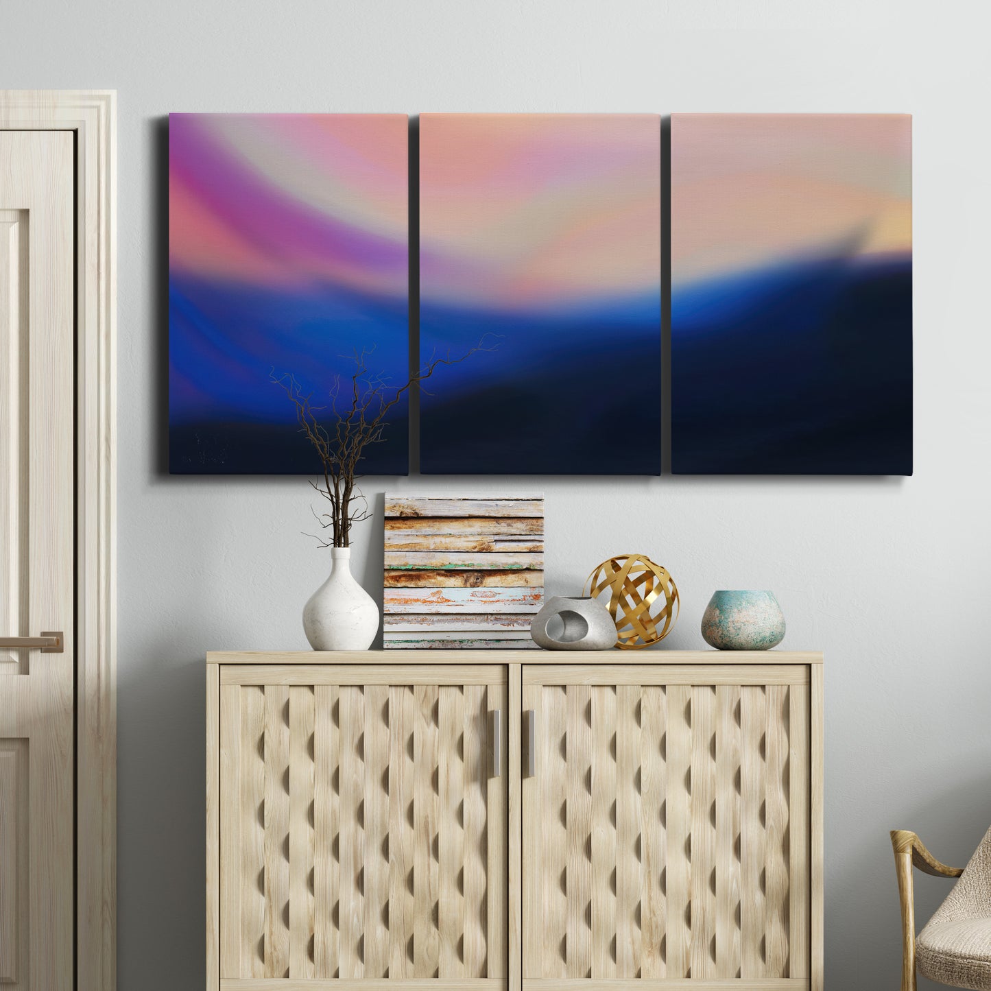 Three-panel canvas wall art featuring smooth abstract sunset color gradient, displayed above a cabinet in an entryway.