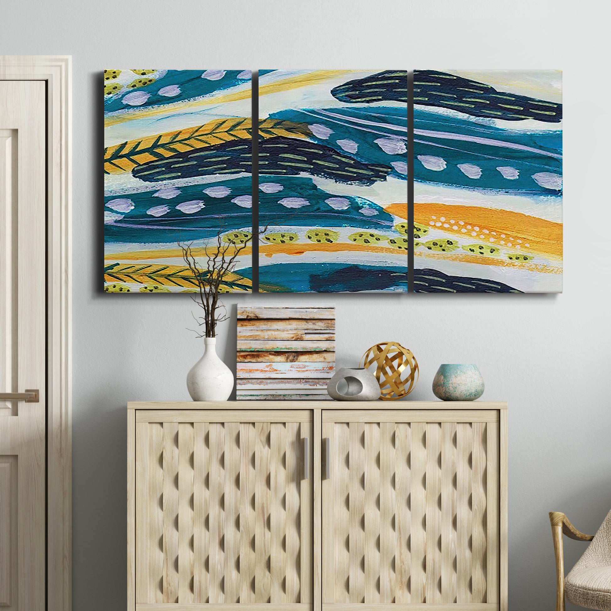 Three-panel canvas wall art featuring feather inspired abstract linear motion, displayed above a cabinet in an entryway.