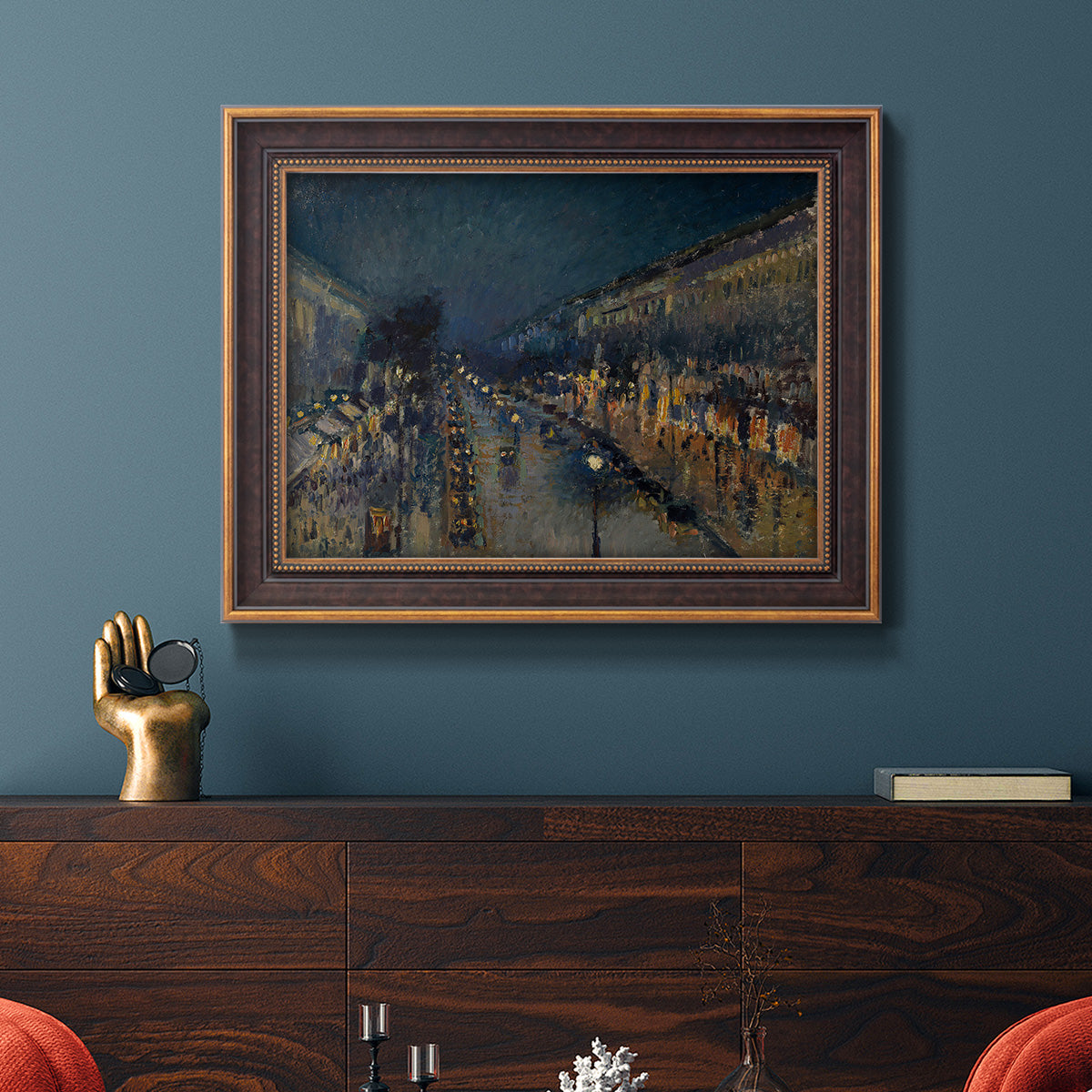 Impressionist nighttime Paris street scene by Camille Pissarro in an ornate bronzed mahogany wood frame displayed in a dark-toned interior setting.