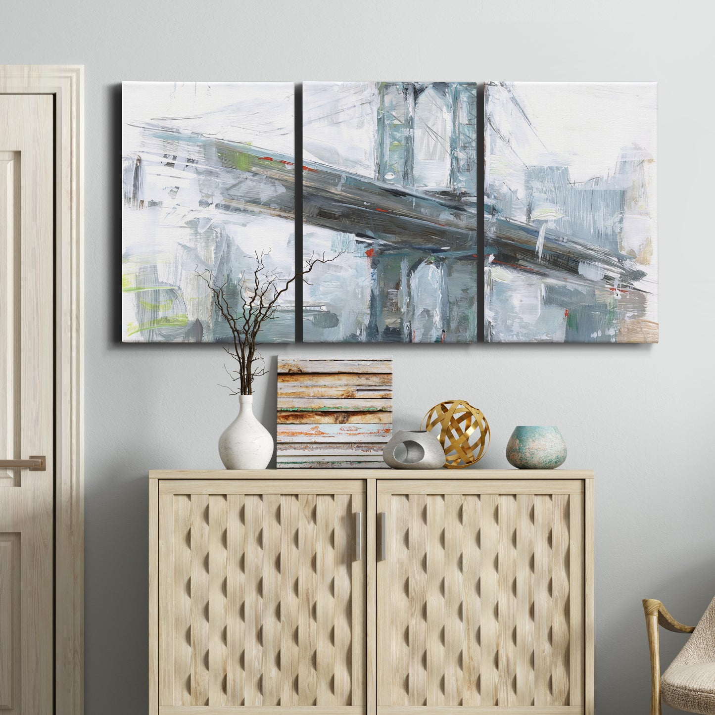 Three-panel canvas wall art featuring urban cityscape with architectural forms, displayed above a cabinet in an entryway.