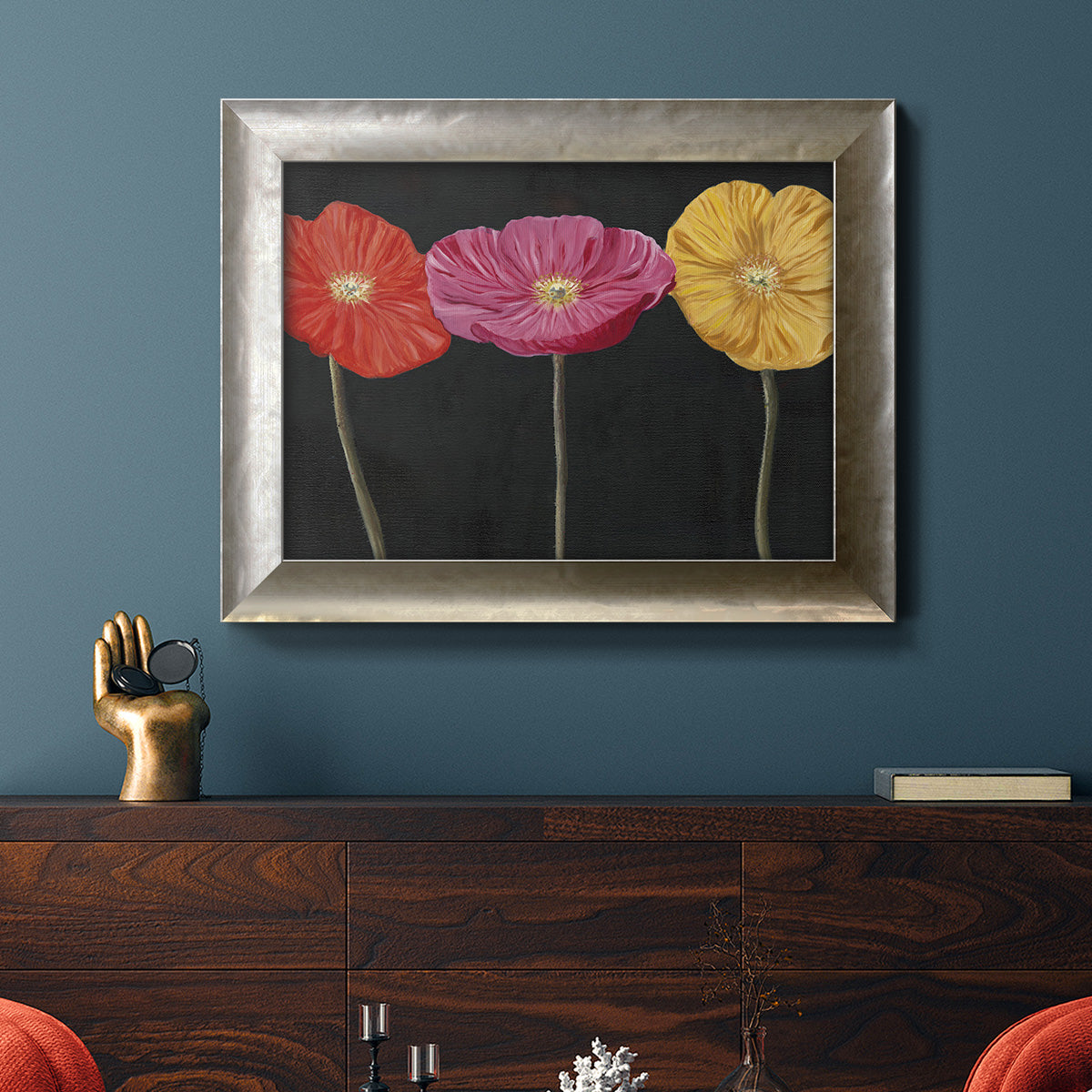 Contemporary poppy flower artwork in an ornate mottled silver frame displayed in a dark-toned interior setting.