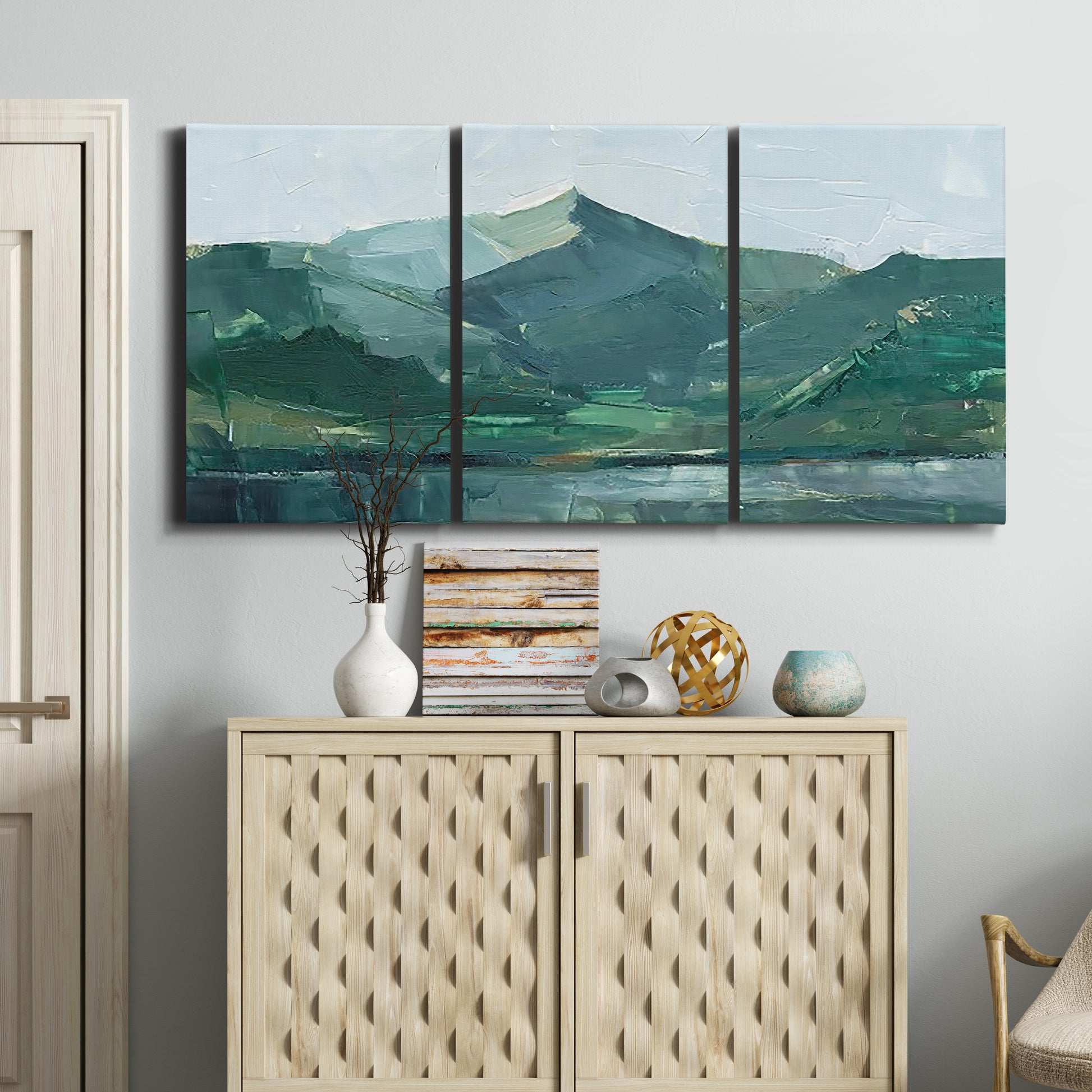 Three-panel canvas wall art featuring muted mountain range in grey tones, displayed above a cabinet in an entryway.