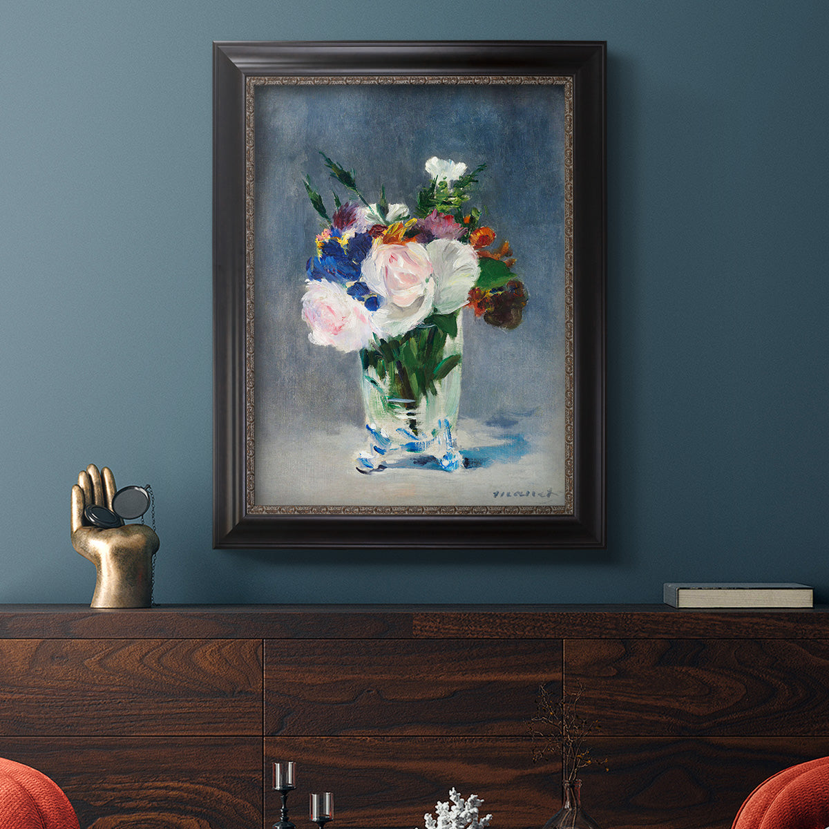 Impressionist floral still life painting by Claude Monet in an ornate black frame with gilded inner detail displayed in a dark-toned interior setting.