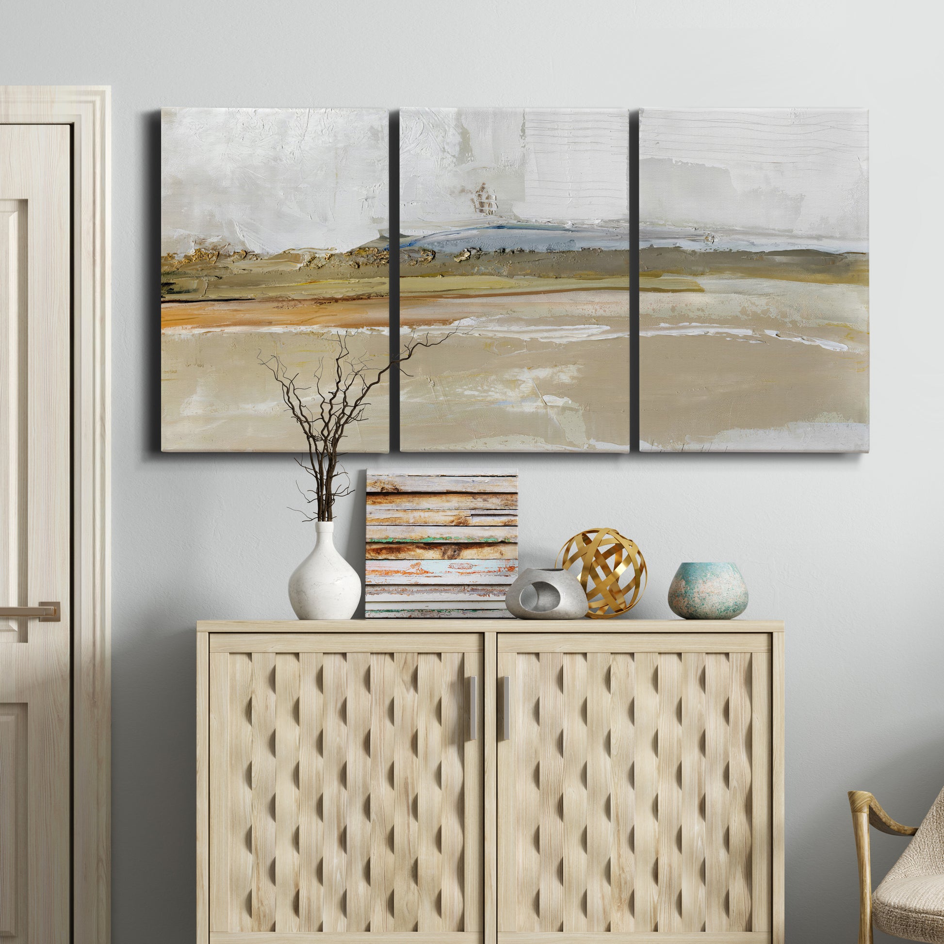 Three-panel canvas wall art featuring golden hour light over landscape, displayed above a cabinet in an entryway.