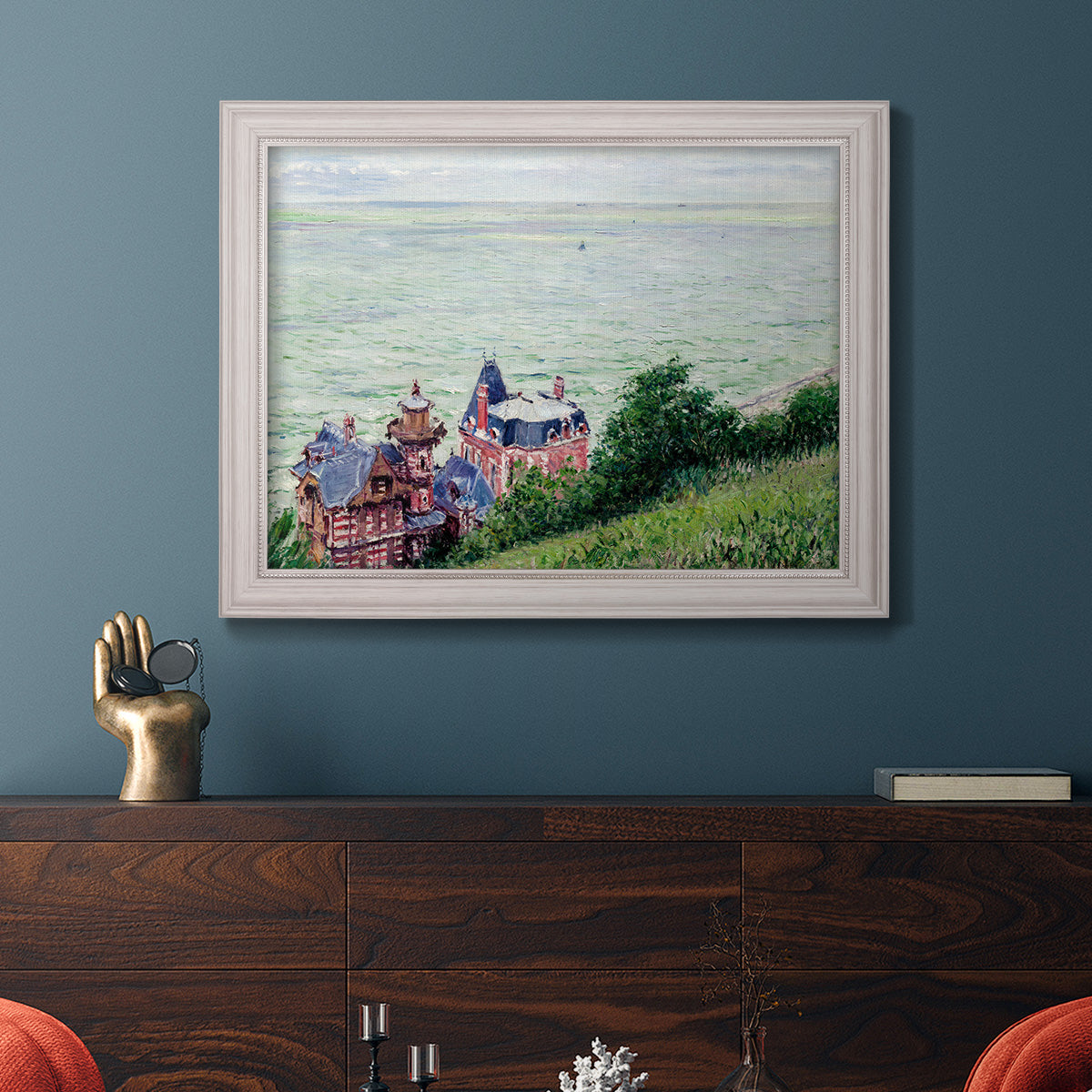 Impressionist coastal villas landscape by Gustave Caillebotte in an ornate weathered white frame displayed in a dark-toned interior setting.