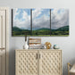Three-panel canvas wall art featuring pastoral mountain landscape in blue, displayed above a cabinet in an entryway.