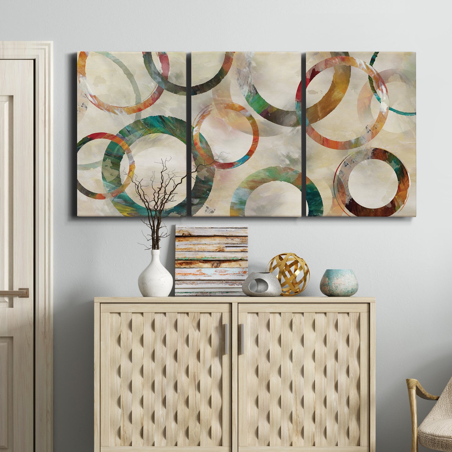 Three-panel canvas wall art featuring geometric circular abstract design, displayed above a cabinet in an entryway.