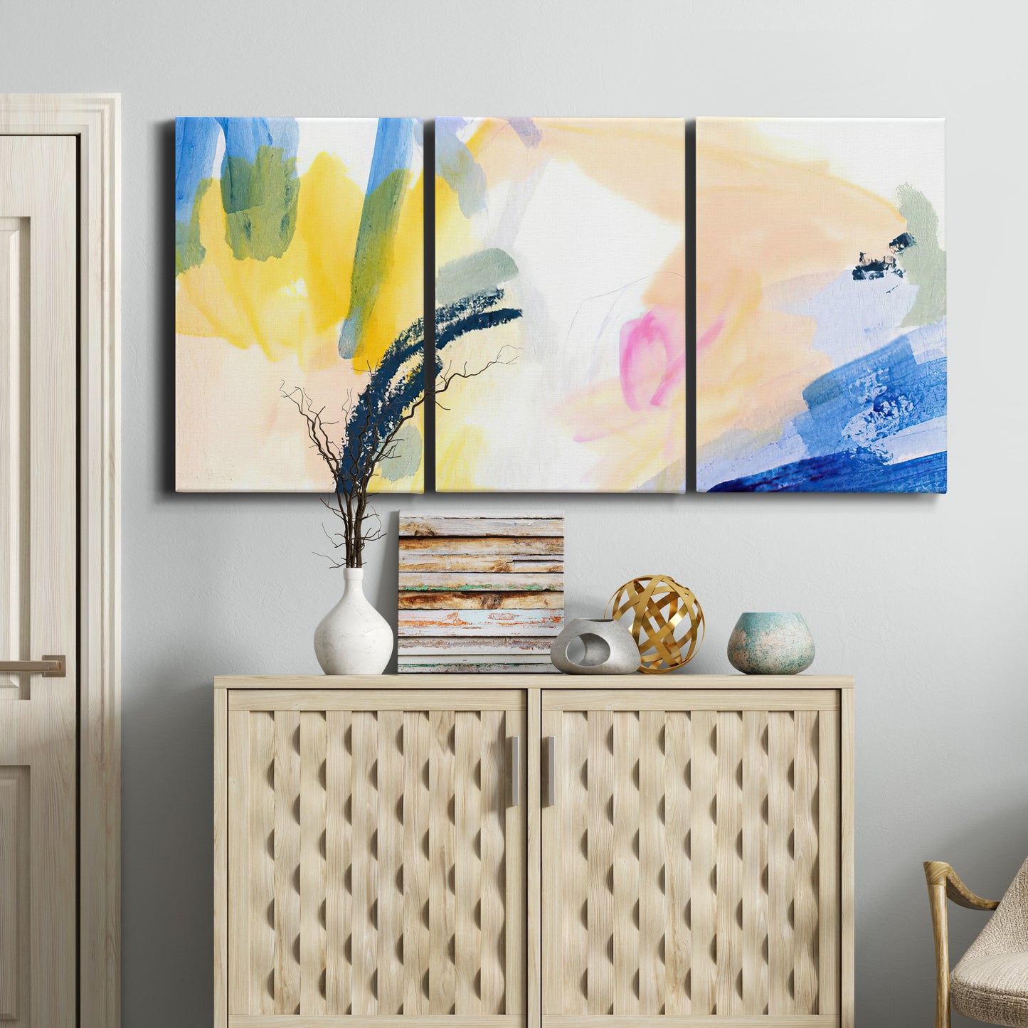 Three-panel canvas wall art featuring bright abstract candy colored strokes, displayed above a cabinet in an entryway.