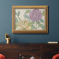 Contemporary peony flower illustration in an ornate antique gold frame displayed in a dark-toned interior setting.