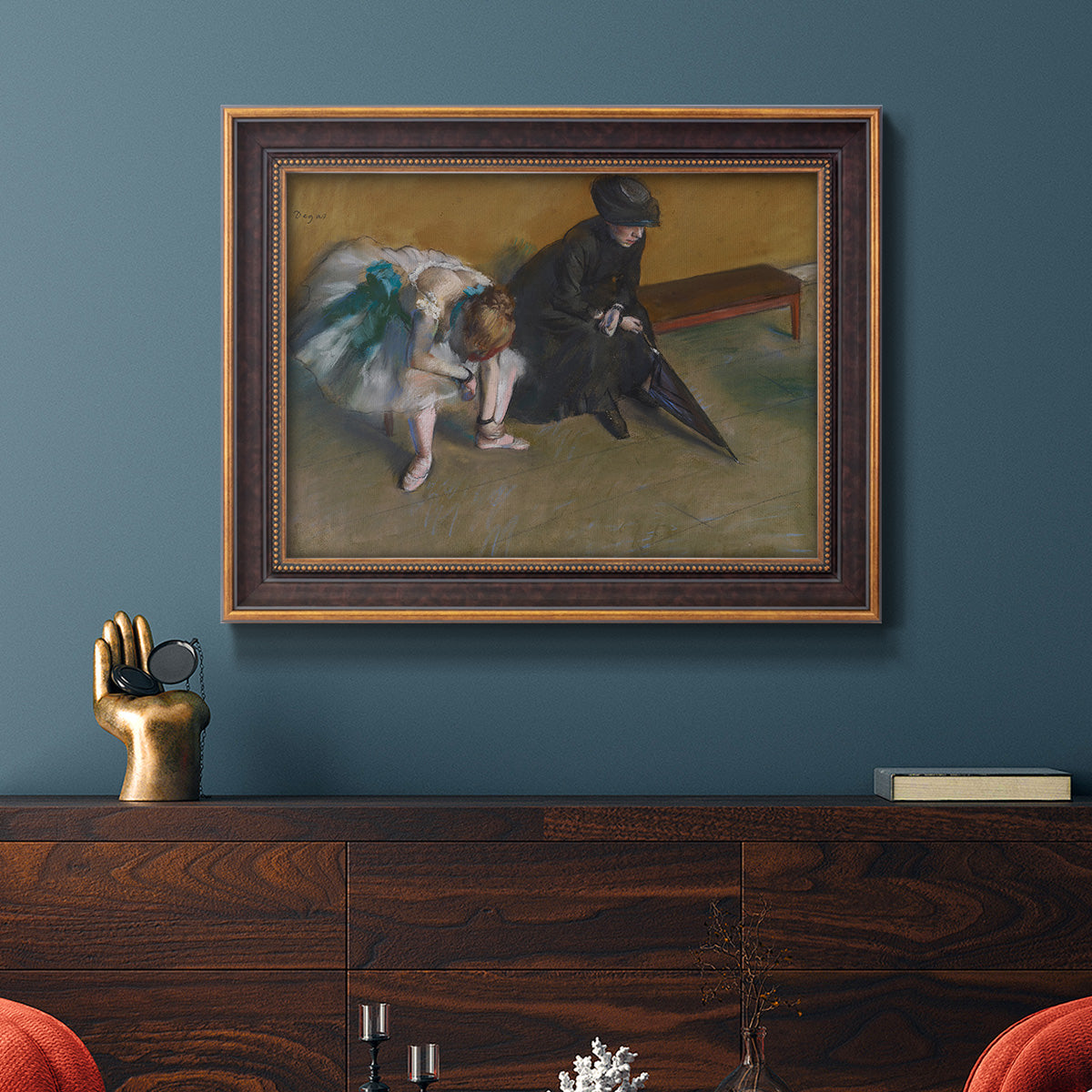 Impressionist portrait of a seated woman by Edgar Degas in an ornate bronzed mahogany wood frame displayed in a dark-toned interior setting.
