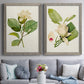 Set of two gray barnwood framed canvas prints depicting paired traditional botanical paintings with large pale petals, leafy branches, and soft watercolor shading above a sofa in a contemporary living room.