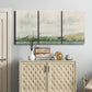 Three-panel canvas wall art featuring riverbank landscape with trees, displayed above a cabinet in an entryway.