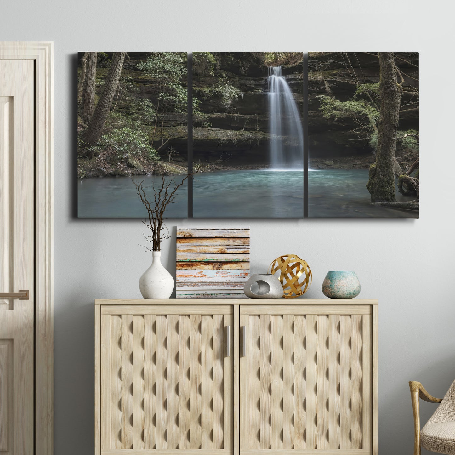 Three-panel canvas wall art featuring waterfall cascading through forest, displayed above a cabinet in an entryway.