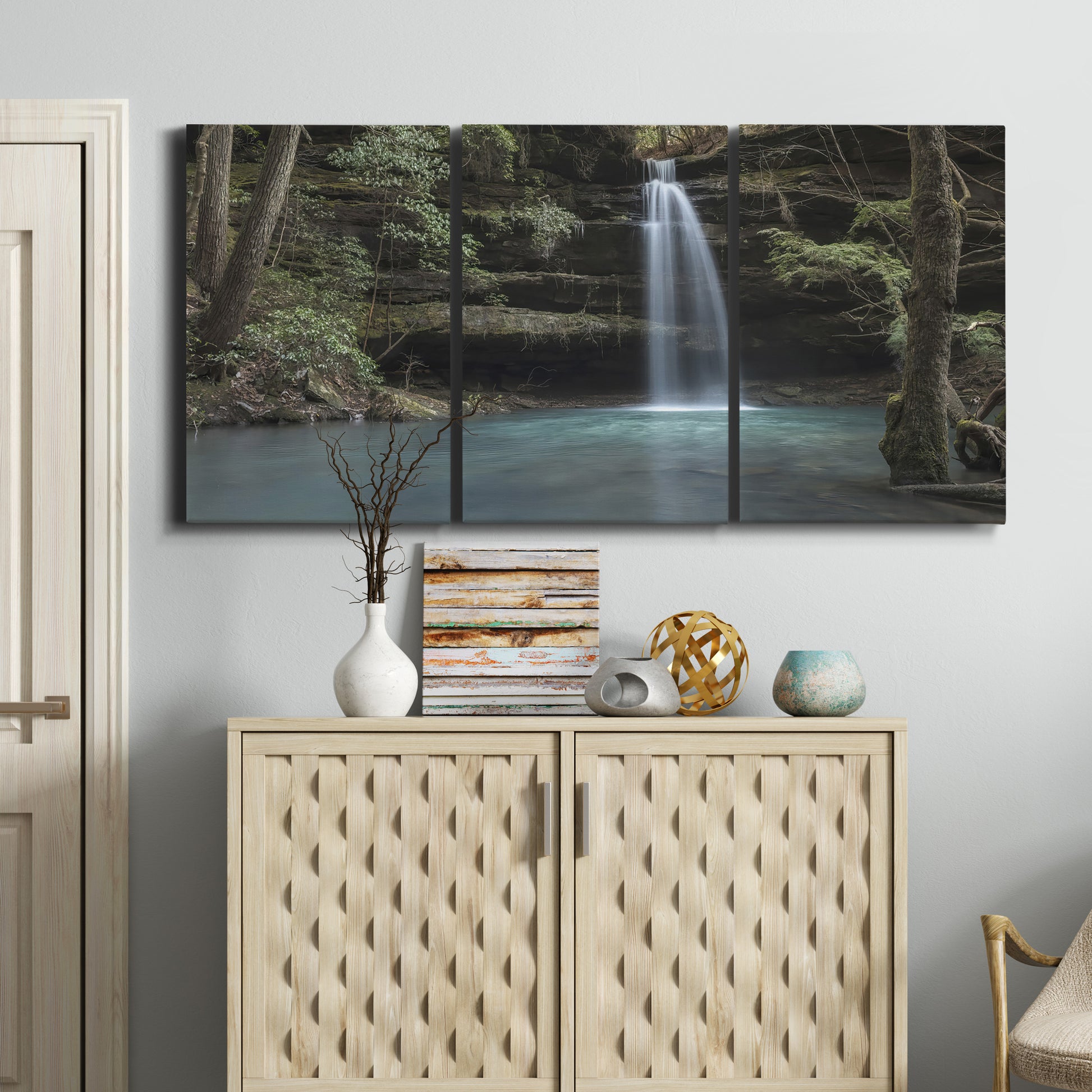 Three-panel canvas wall art featuring waterfall cascading through forest, displayed above a cabinet in an entryway.