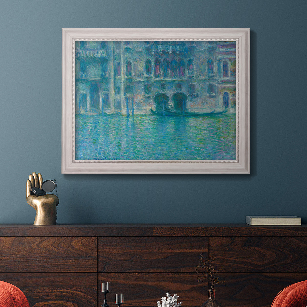 Impressionist Venetian palace waterfront scene by Claude Monet in an ornate weathered white frame displayed in a dark-toned interior setting.