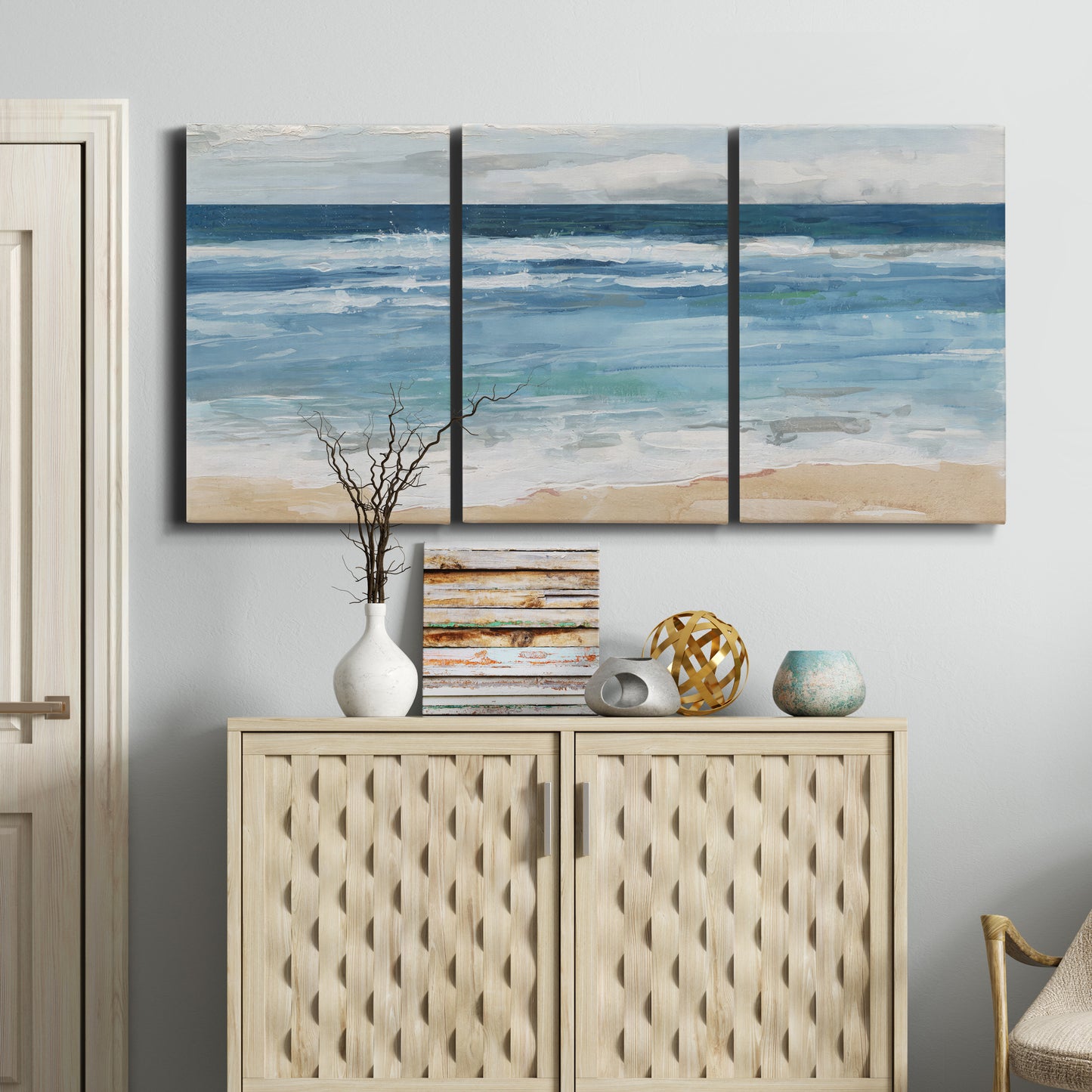 Three-panel canvas wall art featuring rolling ocean waves near shore, displayed above a cabinet in an entryway.
