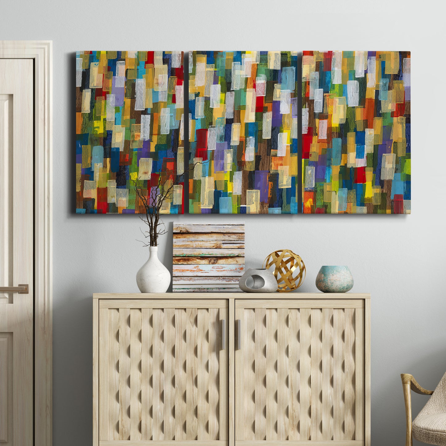 Three-panel canvas wall art featuring colorful confetti style abstraction, displayed above a cabinet in an entryway.